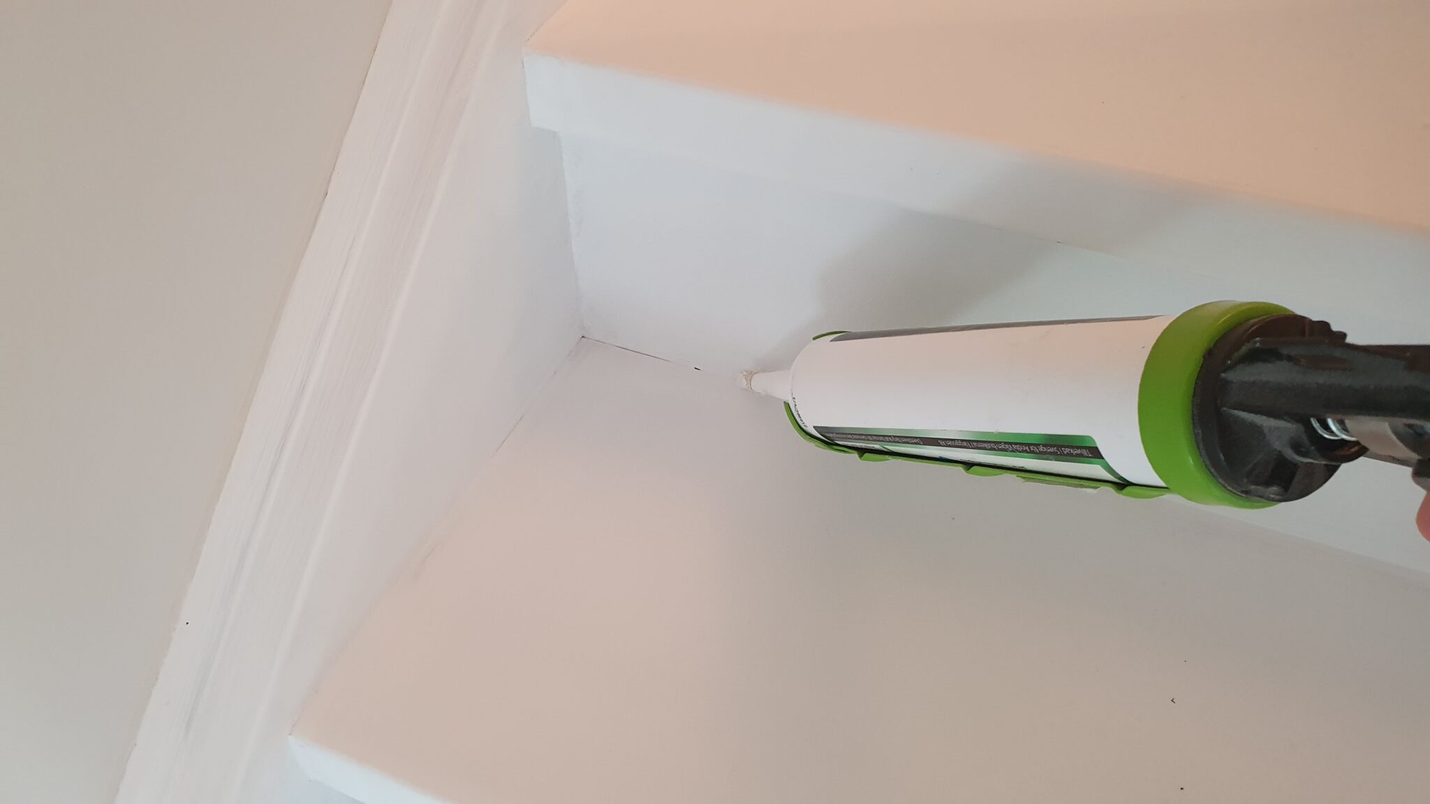 Caulking stairs after they have been primed.