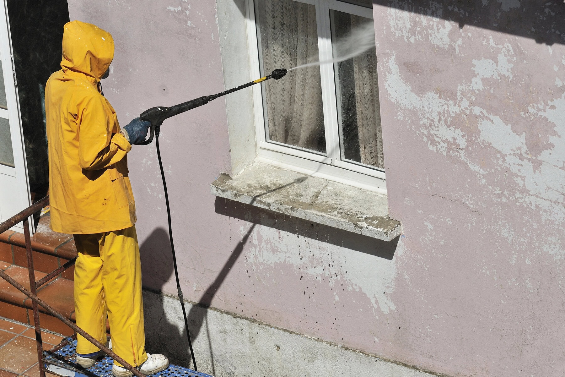 Man pressure washing stucco exterior