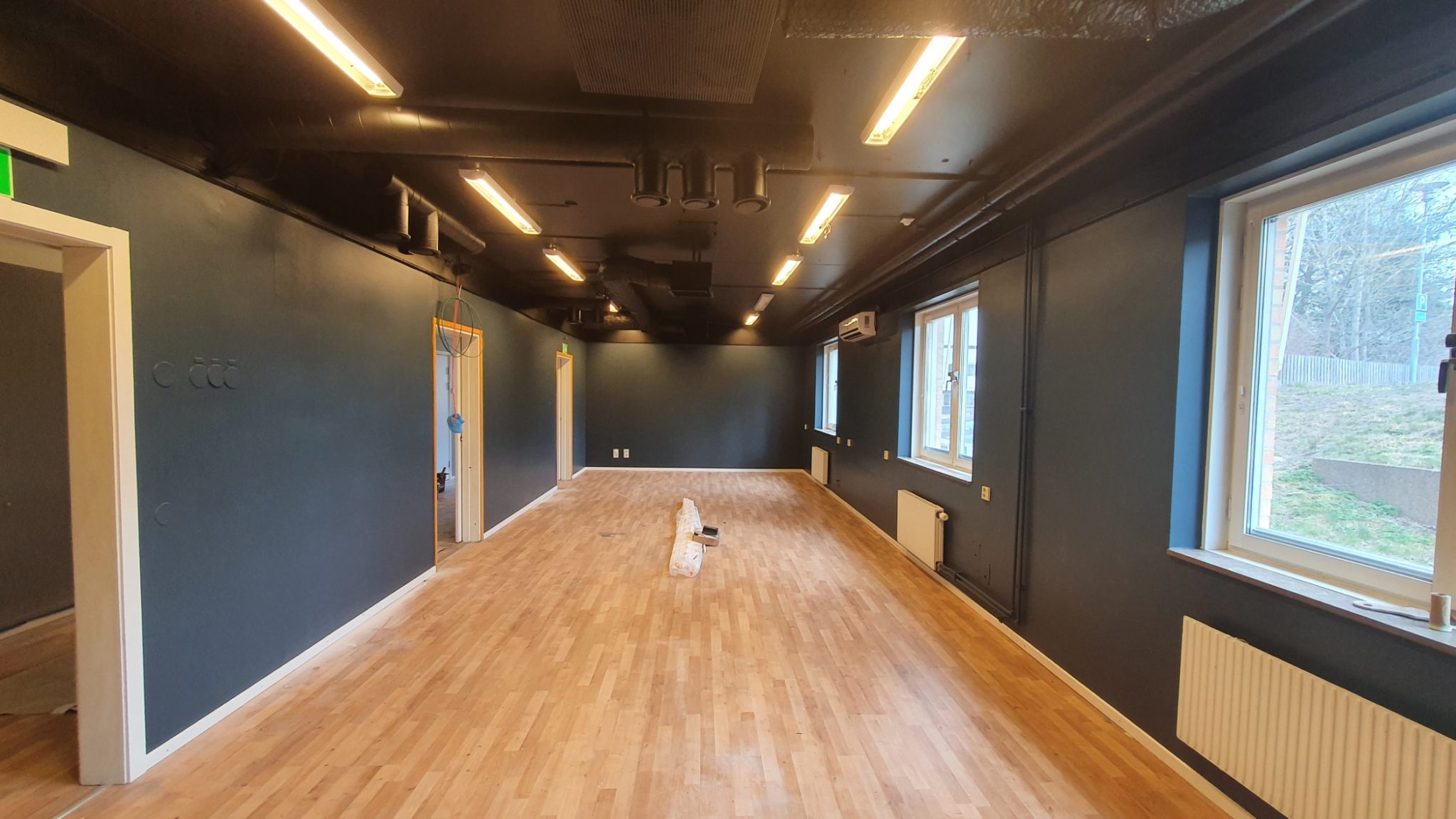 Professional gym ceiling with exposed pipes and ducts painted with paint sprayer