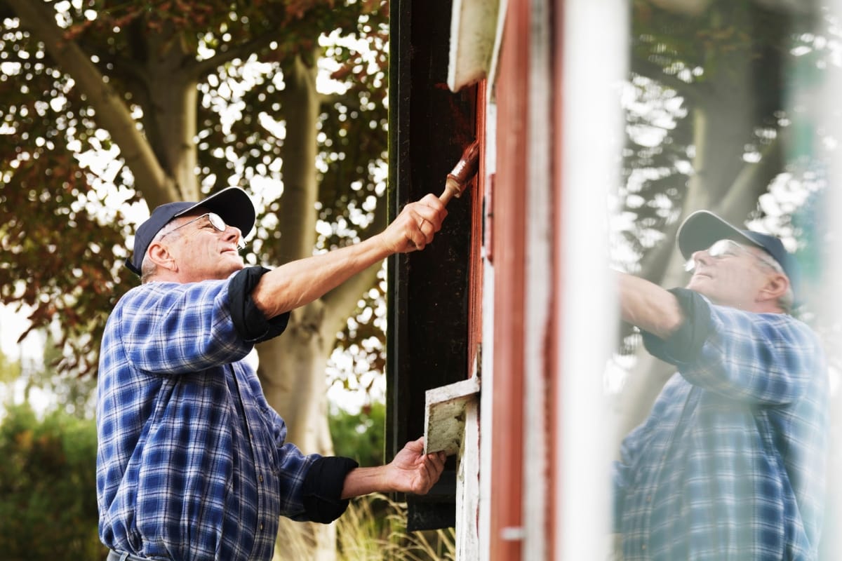 man painting siding